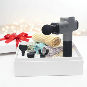 Massage gun with attachments and towels on a white background