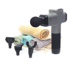 Massage gun with attachments and towels on a white background