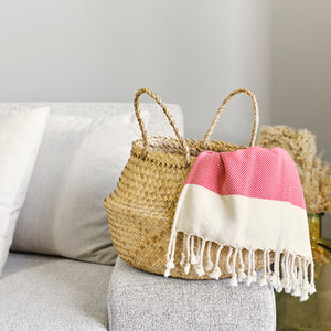 Woven basket with a pink and white striped towel on a gray surface
