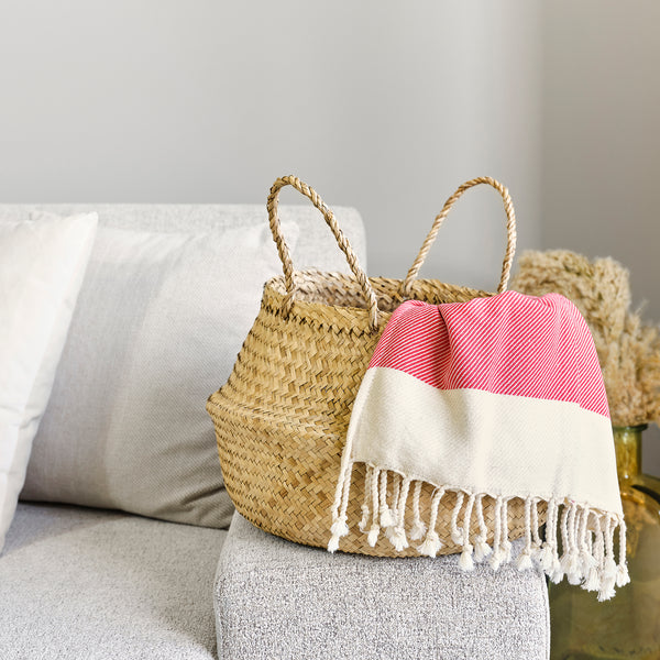 Woven basket with a pink and white striped towel on a gray surface