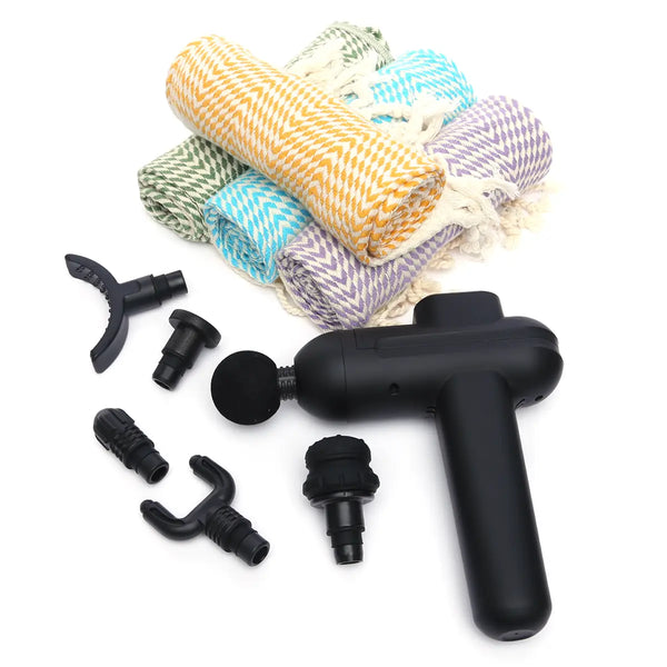 Black massage gun with various attachments and colorful rolled-up Turkish Towels on a white background
