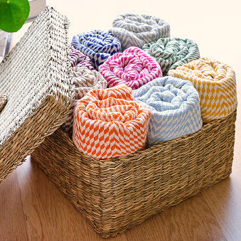 Woven storage basket with colorful boho-style cushions on a wooden floor.